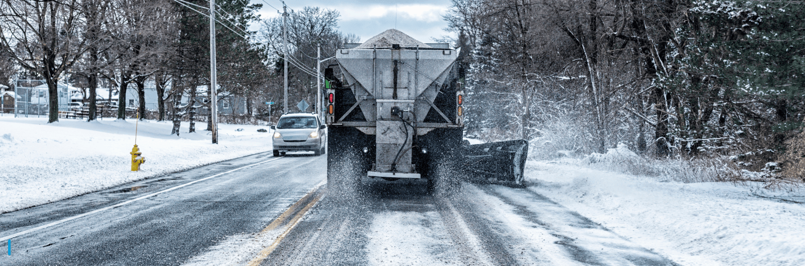 Truck salting road on a snowy day.